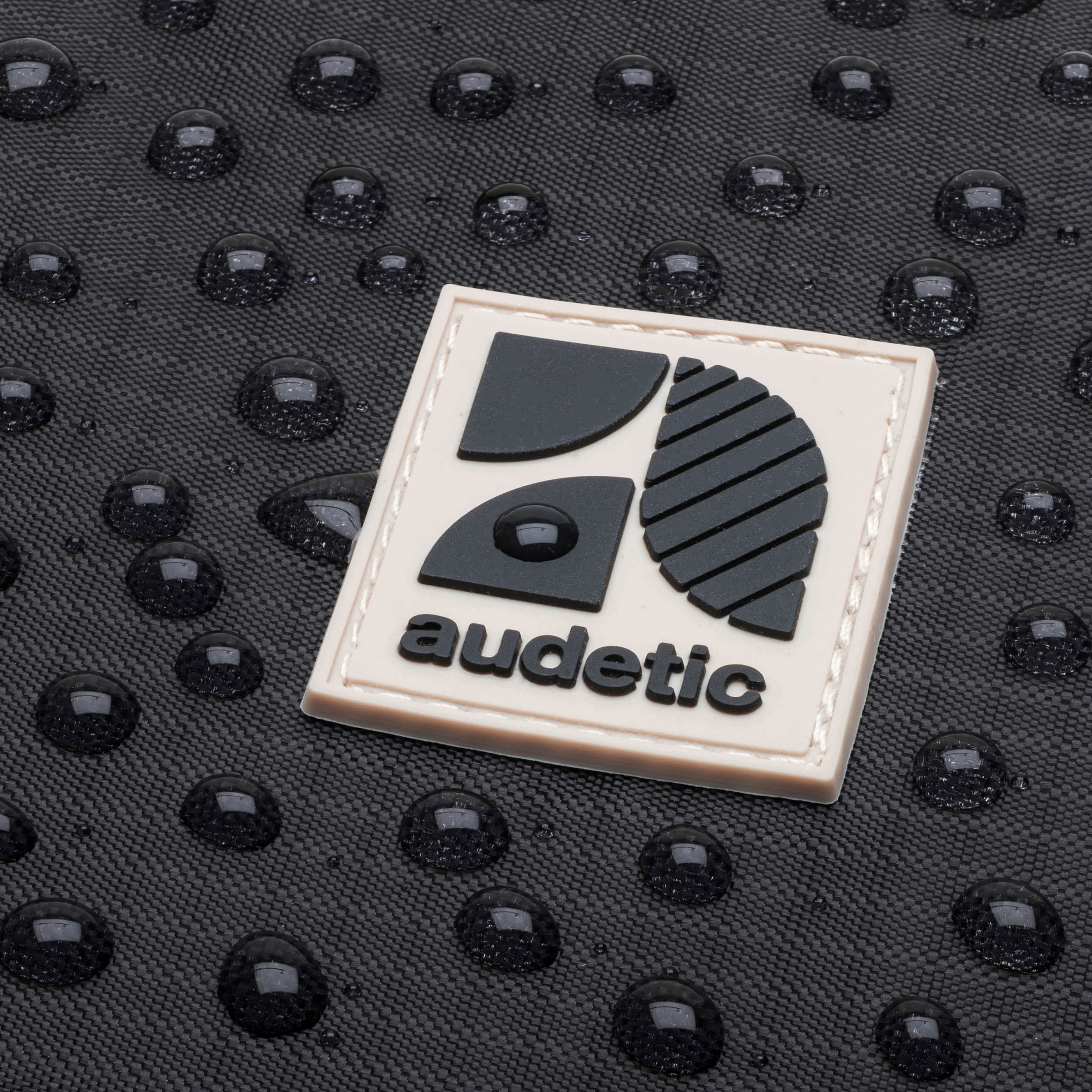 Wasserabweisendes Material der Bauchtasche DRIP mit aufgenähtem audetic-Logo