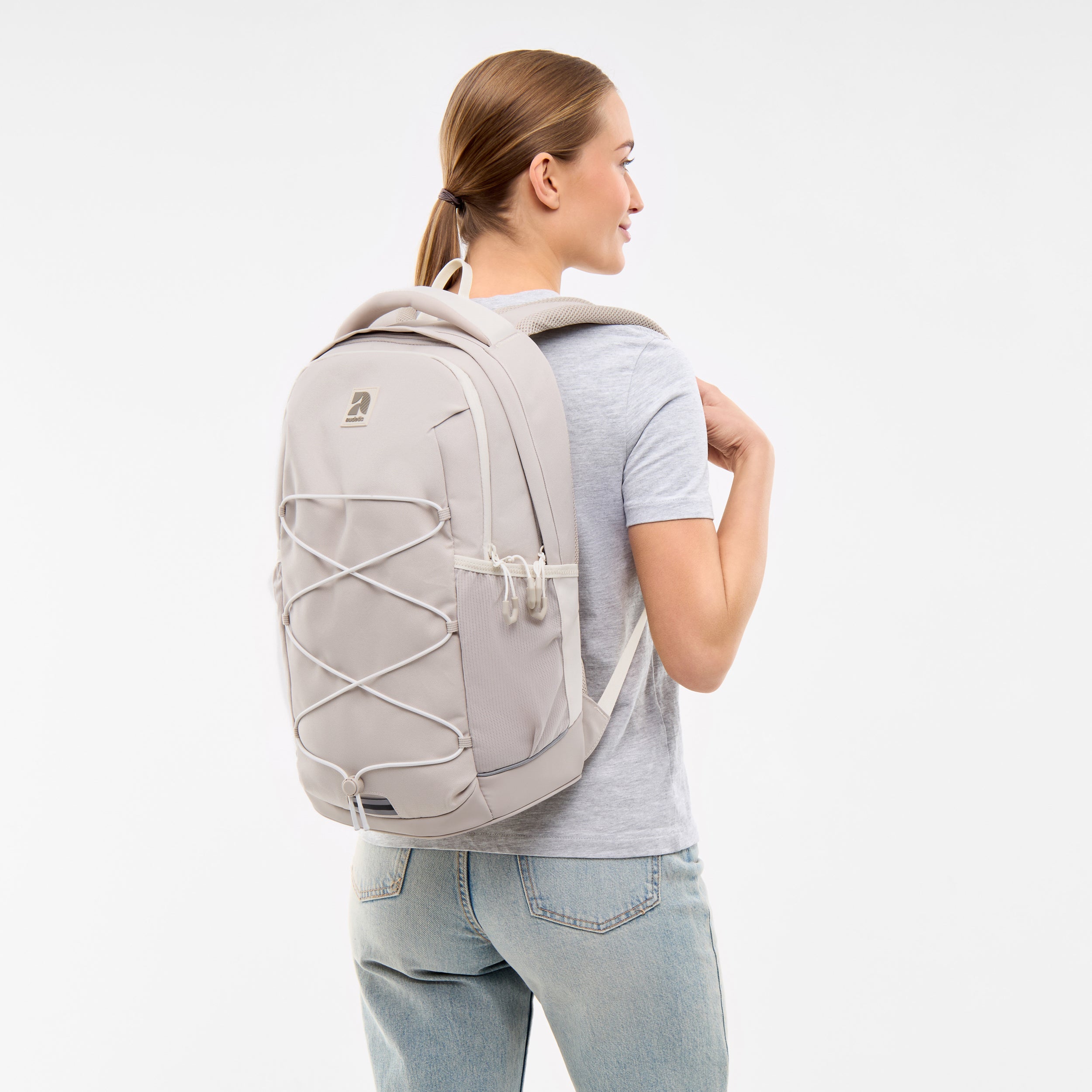 Teenager-Mädchen mit blondem Pferdeschwanz trägt sandfarbenen Schulrucksack AERO von Audetic