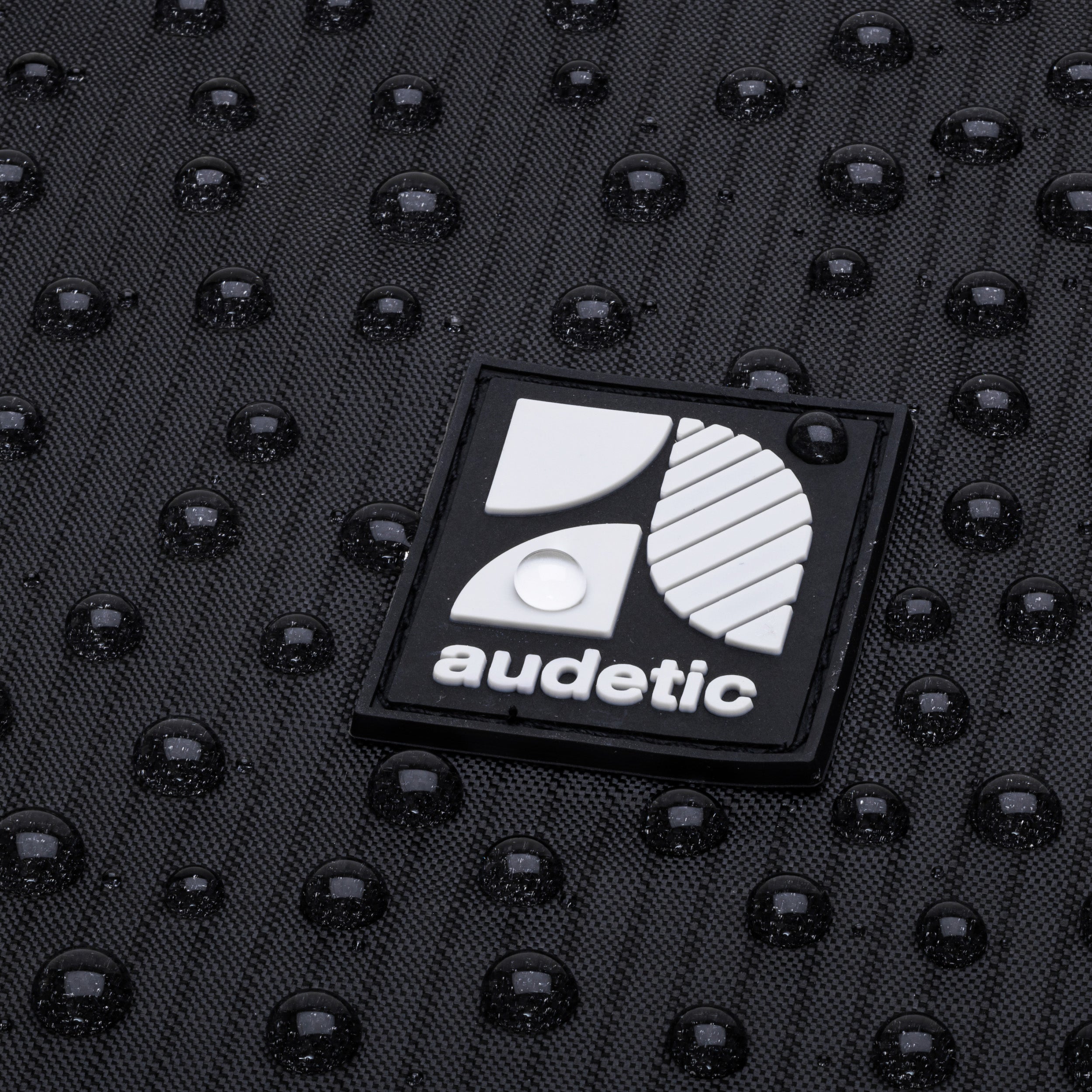 Wasserabweisende schwarze Stoffoberfläche mit weißen 'audetic' Logo auf Turnbeutel FIT