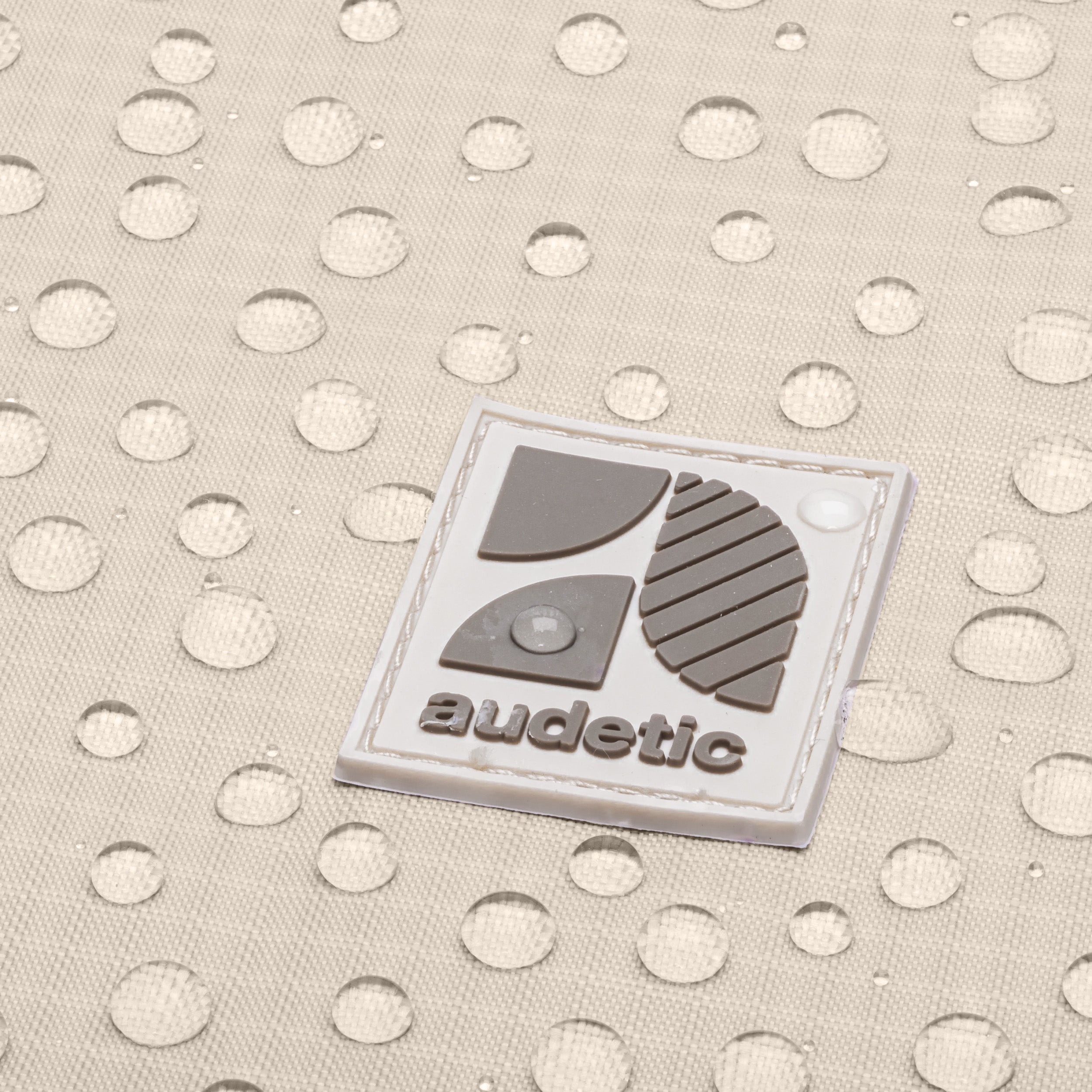 Wasserabweisendes beige Material mit audetic Logo und Wassertropfen