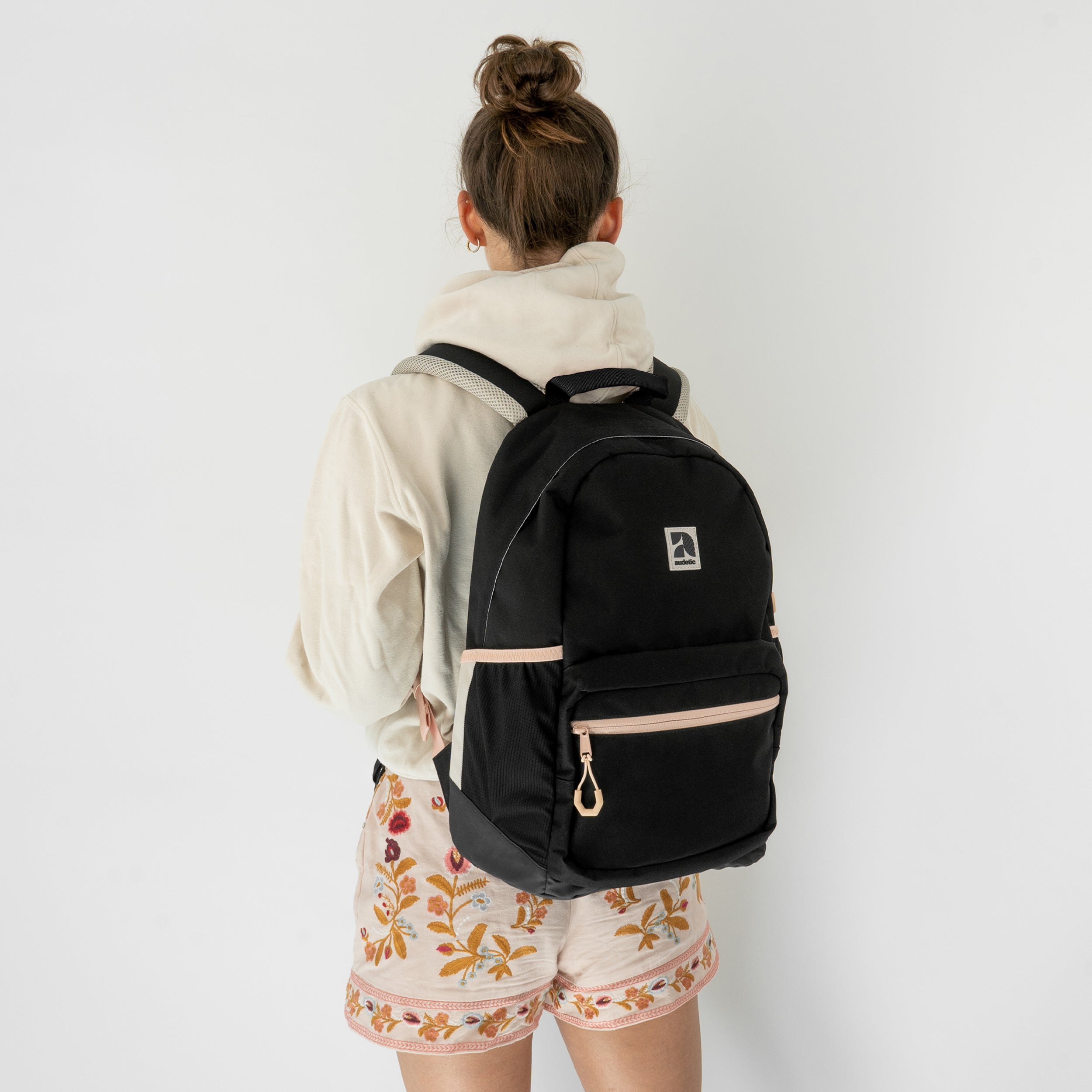 Mädchen von hinten mit schwarzem Audetic Schulrucksack FLEX mit rosafarbenen Details