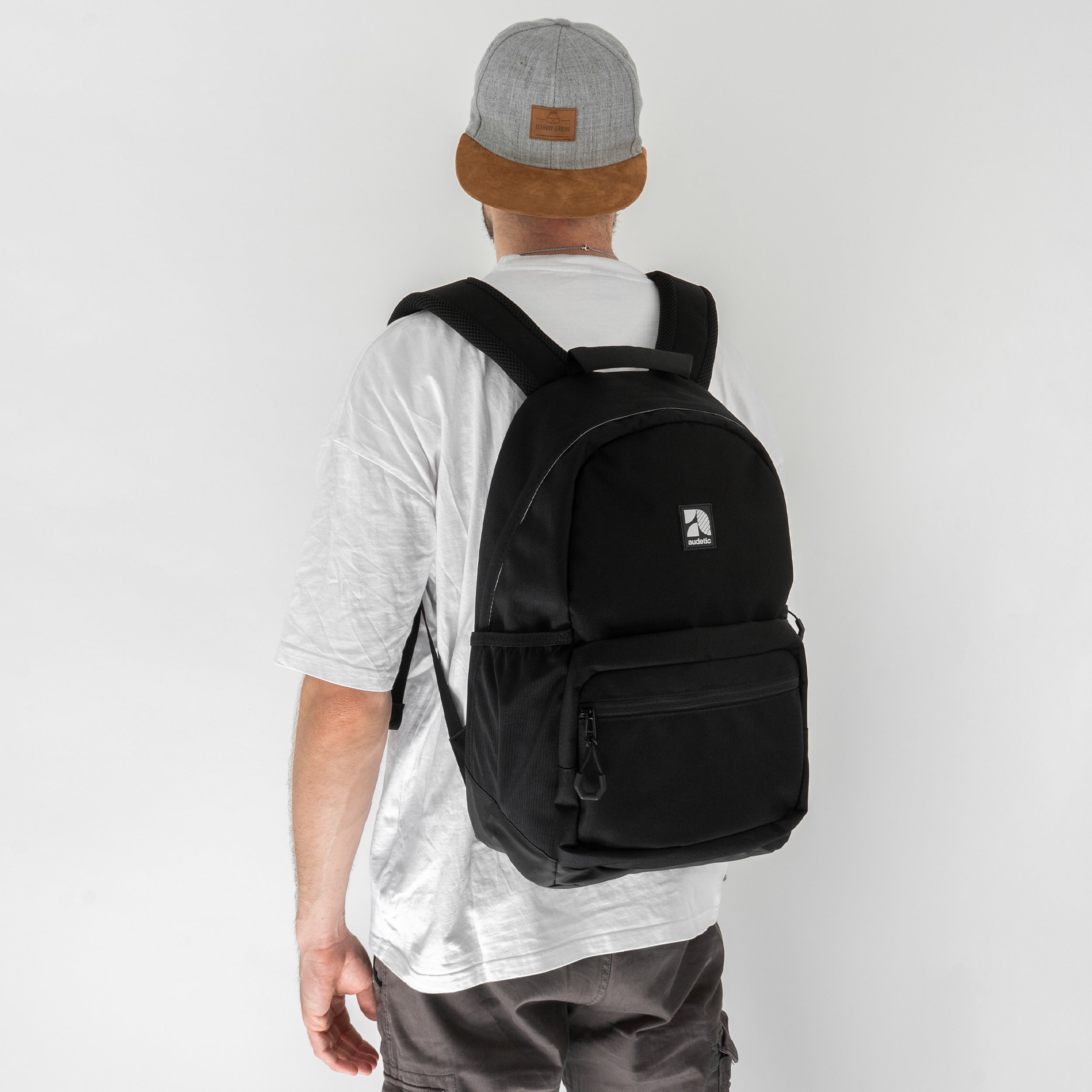Teenager trägt schwarzen audetic Schulrucksack FLEX mit gepolsterten Trägern und Fronttasche