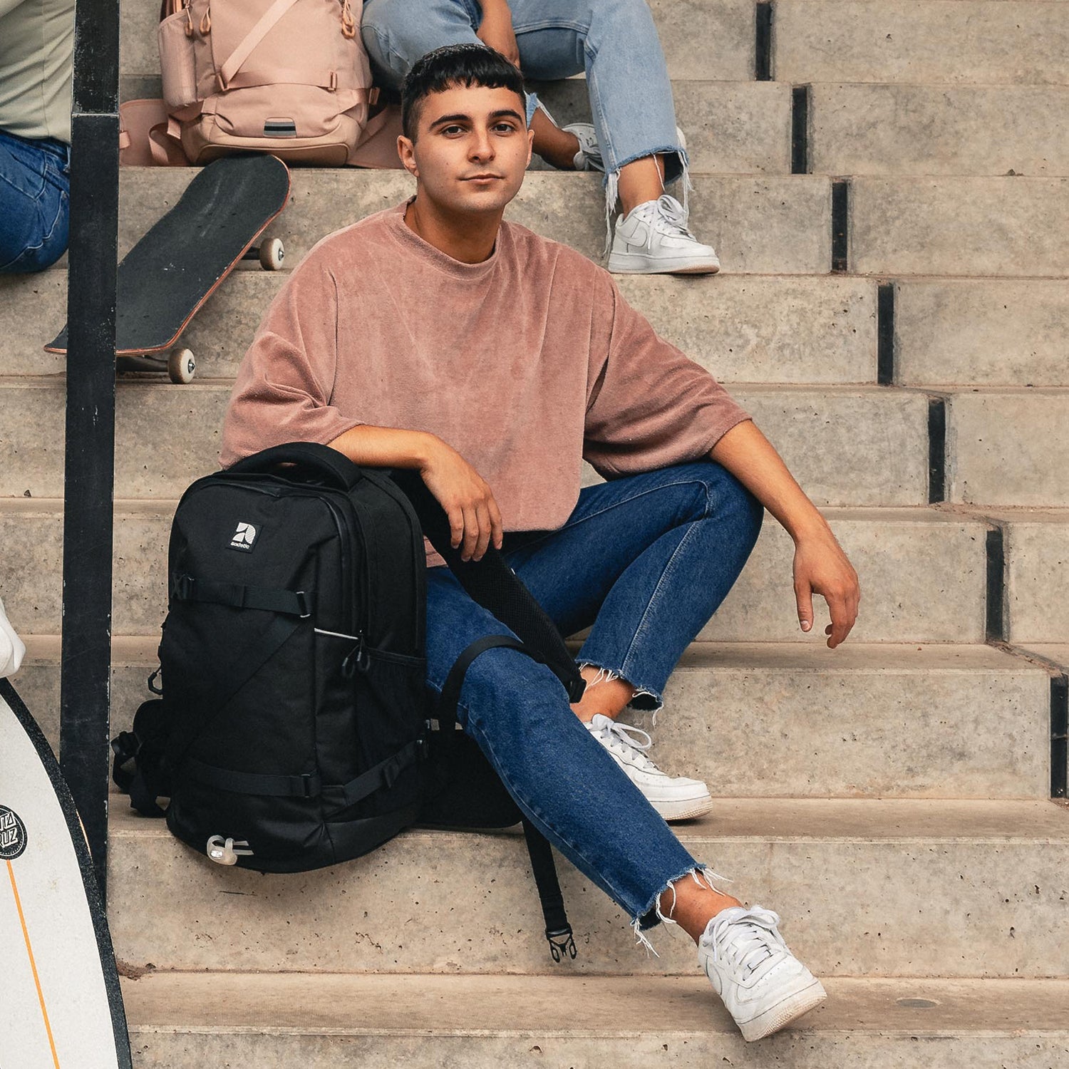 Jugendlicher sitzt auf Treppen neben schwarzem Schulrucksack COSMO von audetic