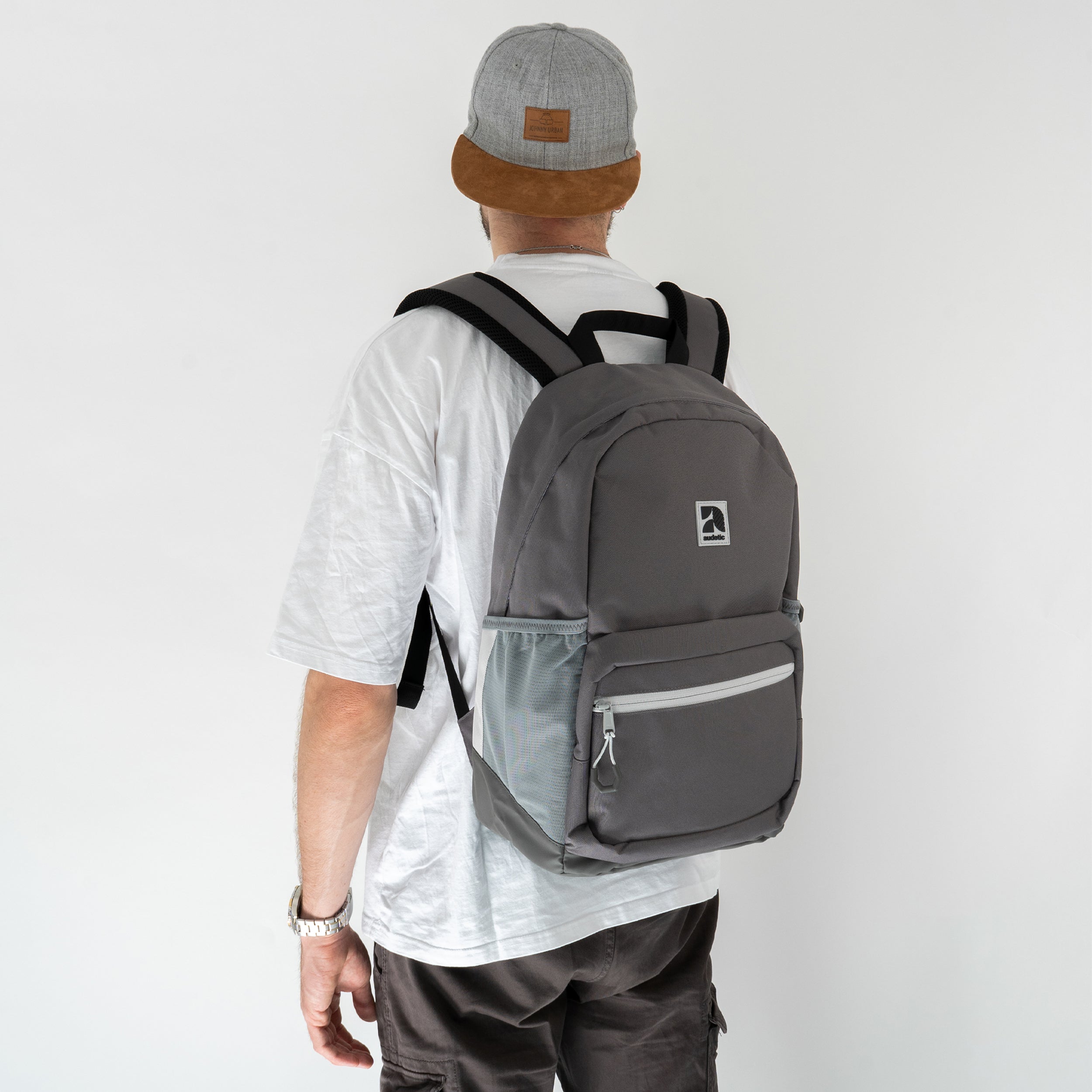 Jugendlicher trägt grauen Schulrucksack FLEX von audetic mit Netzseitentaschen und vorne Reißverschlusstasche